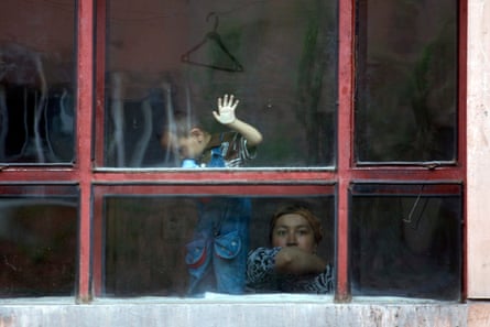 A Uighur woman look out from the window of an apartment Urumqi, China.