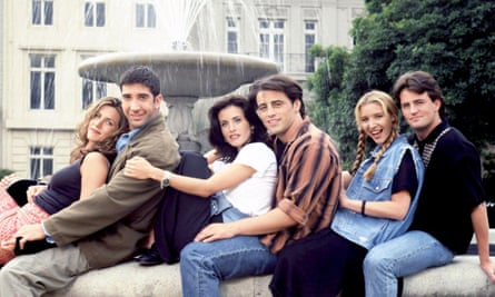 A group of six friends - three women and three men - sitting by a fountain hugging each other