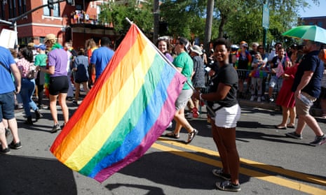 person holds rainbow flag during parade