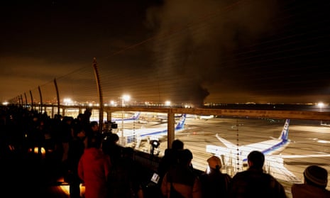 Passagiers kijken vanaf een observatiedek naar een brandende Japan Airlines A350 op de internationale luchthaven Haneda in Tokio.