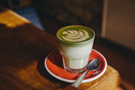 A green and white matcha latte with a pretty design on the surface