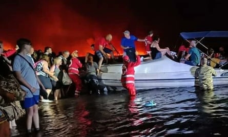 A Cruz Vermelha Helênica ajuda cidadãos e turistas a se mudarem para um local seguro durante incêndios florestais em Rodes.