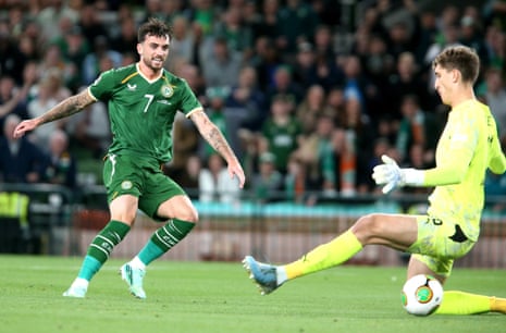 Troy Parrott (L) of Ireland scores the opening goal against goalkeeper Florian Wiegele of Austria.