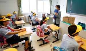 A teacher distributes epidemic prevention materials for students at Fengtai No 1 Primary School in Beijing Photograph: China News Service/Getty Images