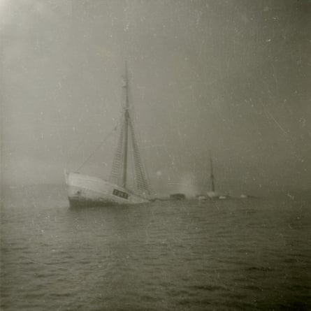 Black and white image of a ship with a mast sinking
