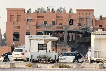 Charred and damaged building with vehicles in front