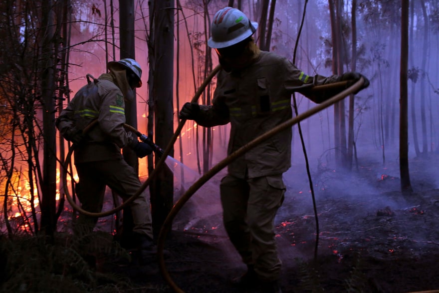 Firefighters work to prevent a fire reaching the village of Avelar Photograph: Armando Franca/AP