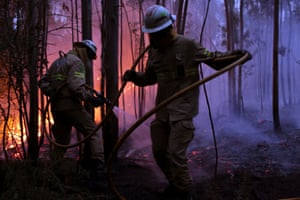 Portuguese National Republican Guard firefighters work to stop a forest fire from reaching the village of Avelar