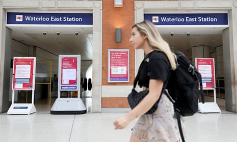 Woman walks past the gate of Waterloo East Station