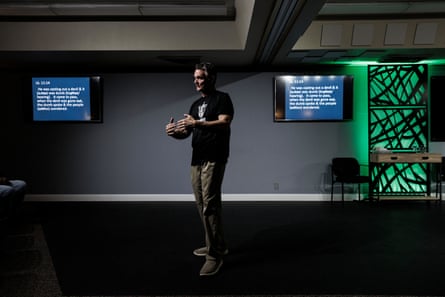 man gestures as he speaks in front of screens with bible verses