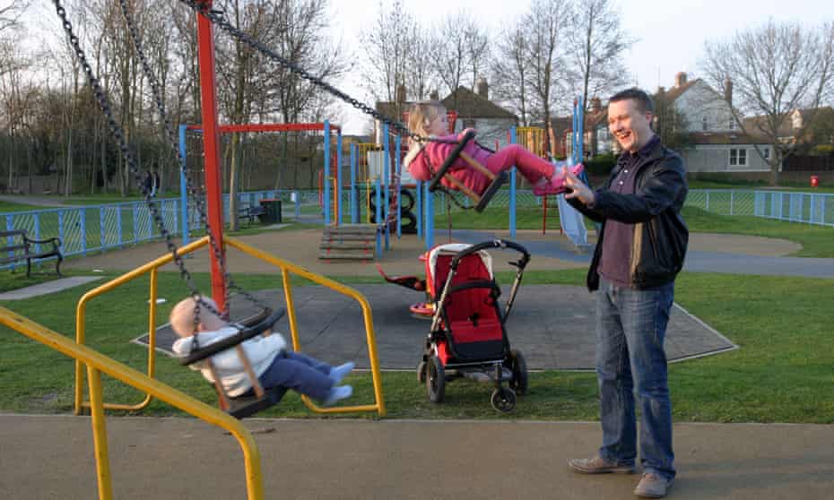 A man with his children in a playground. Hundreds are being closed by local authorities across England.