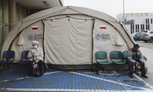 People sit outside a medical tent used for COVID-19 testing near a hospital in Warsaw, Poland, on Wednesday, 4 November, 2020.
