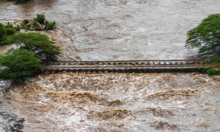Brown flood waters cover a bridge 