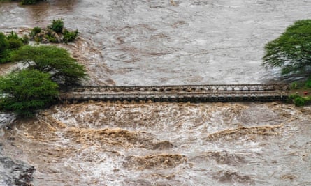 Brown flood waters cover a bridge