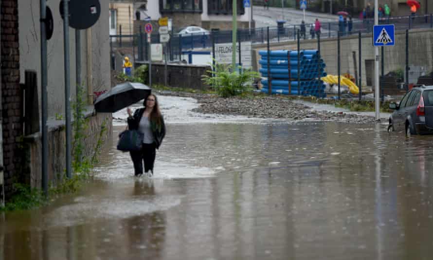 Eine Frau mit Regenschirm läuft am 14. Juli in Hagen eine überflutete Straße entlang.