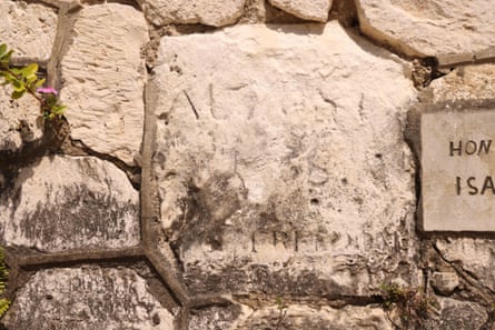 A weathered stone in a wall inscribed with hard-to-decipher lettering