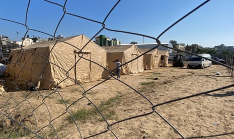 A man stands next to a tent as workers set up a Jordanian field hospital in Khan Younis, southern Gaza Strip.