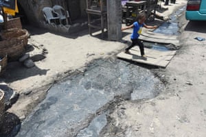 A girl runs past a gutter filled with stagnant water near a malaria testing and treatment session in the Eti-Osa East district of Lagos on 21 April 2016.