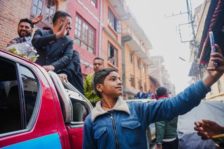 Balen Shah waves while a young supporter takes a photo
