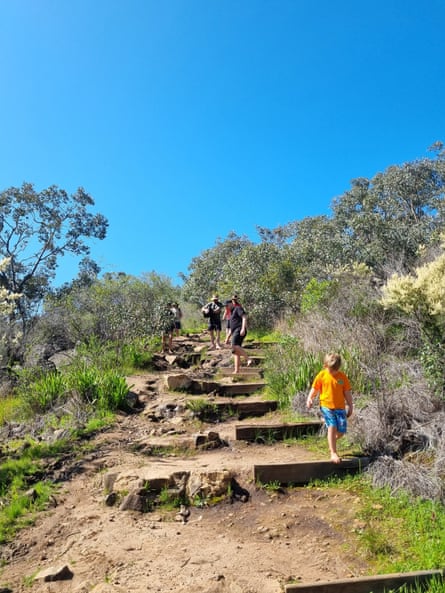 Two people and a boy barefoot hiking on a trail around Perth.