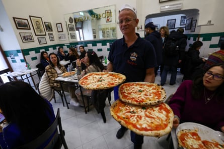 A waiter carries pizzas at L'antica Pizzeria da Michele in Naples