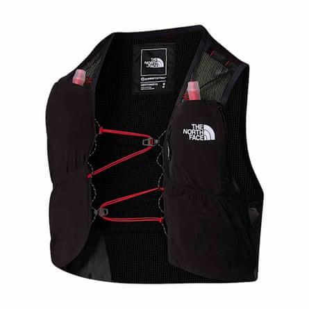 The North Face Summit Series Run Vest. The best has a water pouch mouthpiece appearing out of each breast pocket. The elasticated fastener is red and zigzags across the chest. There is a North Face logo on the left breast. The vest is black.