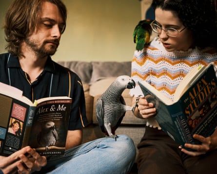 Apollo the African grey parrot sitting appearing to read a book with his owners Dalton Mason and Tori Lacey at home in Florida, US
