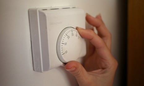 A hand turning down the thermostat