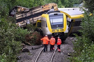 Three people in hi-vis clothing at the site of a train derailment