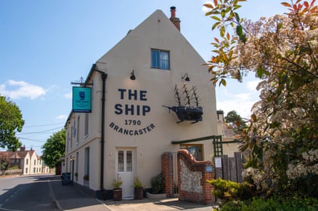 The side of a pub with a ship suspended from the wall.