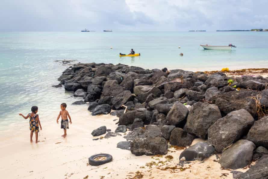 Children play near beach defences along the beach in the Funafuti lagoon