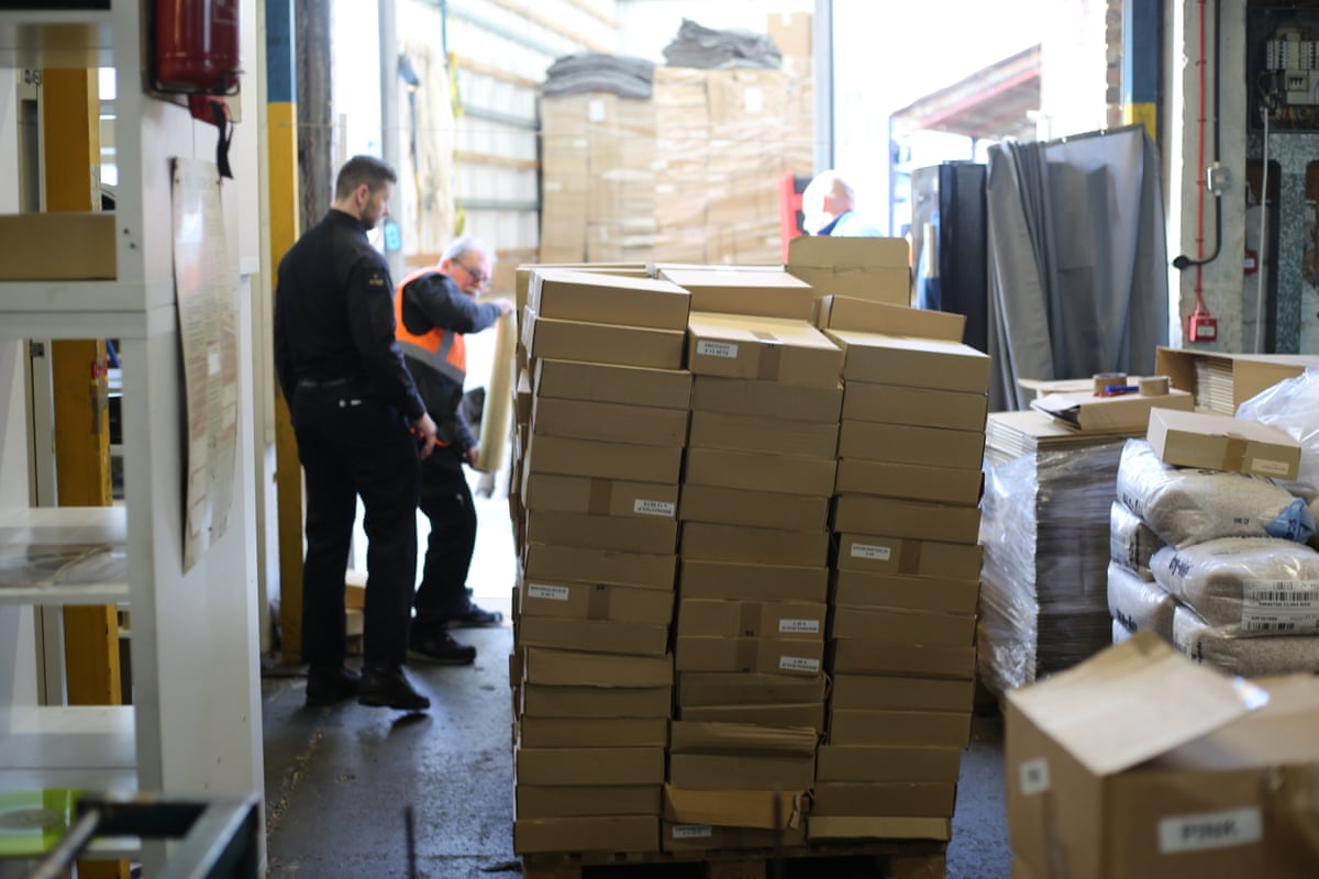 Police officers inspect piles of counterfeit vinyl in a warehouse.