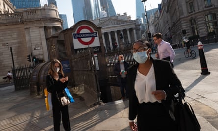Workers in their masks make their way down the streets near the Bank of England in the City of London