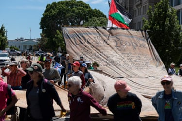 people hold a giant banner with the preamble to the constitution on it