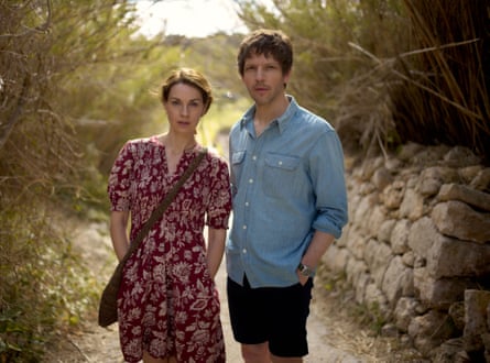 A woman in a flowery dress stands with a man in shorts and a blue shirt