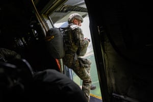 a military paratrooper jumps from an opoen door on an aircraft