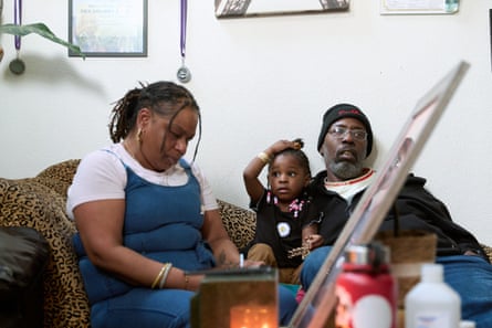 Parents LaTanya Robinson and André Robinson Sr. sit in the living room with their grandchild at their home in Antioch, Calif.