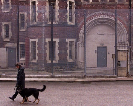 A prison officer walking a police dog in front of the entrance to HMP Strangeways.
