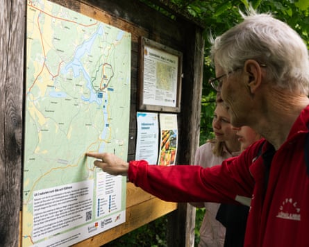 Tore Sjöqvist points out a trail to Oona Verveld and Clara Vikberg on a map attached to a sign post