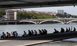 People sit in the shade under a bridge in the center of Lyon, central France. More than half of France was placed on an orange alert for intense heat Monday _ the second-highest level on the scale.