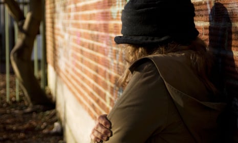 Rear view of a woman standing against a brick wall