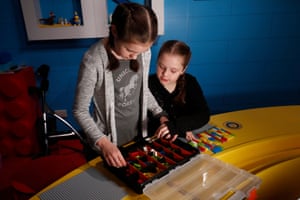 Two children selecting Lego pieces from a box