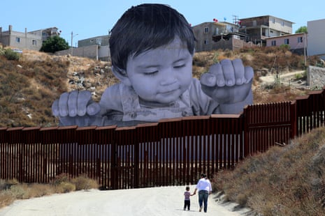  French artist JR’s image of an inquisitive baby looking into the United States over the US-Mexico border wall towards Tecate, California.