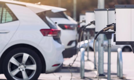 Electric cars are hooked up to charging stations in a parking lot.