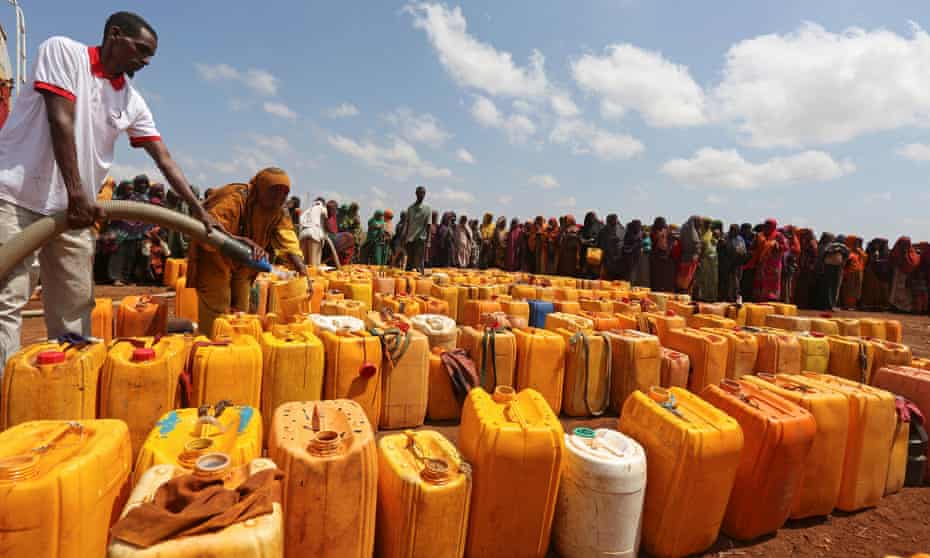 Internally displaced Somali women gather with their jerrycans to receive water