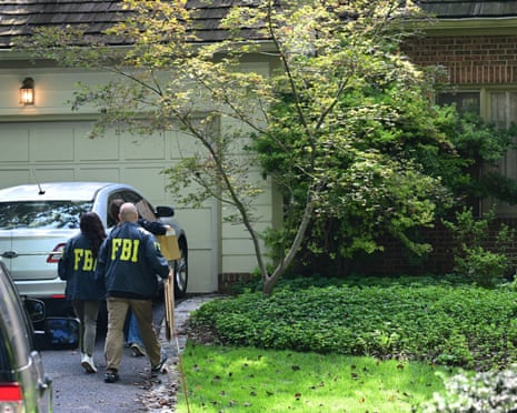 FBI agents carry boxes as they arrive at John Bolton's house.
