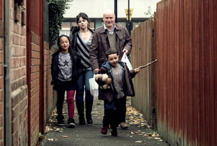 The four walk down a lane behind a row of houses