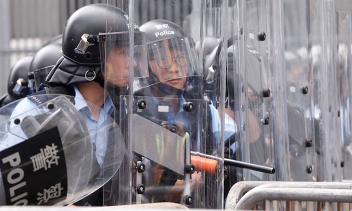 Police officers stand behind riot shields during a demonstration against a proposed extradition bill.