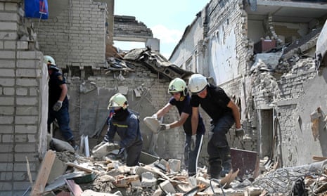 Rescuers work on the ruins of a school building, partially destroyed by two rockets.
