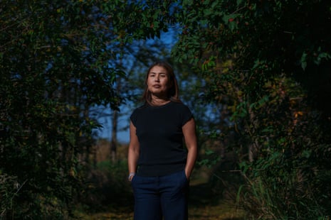 A woman poses outside among trees